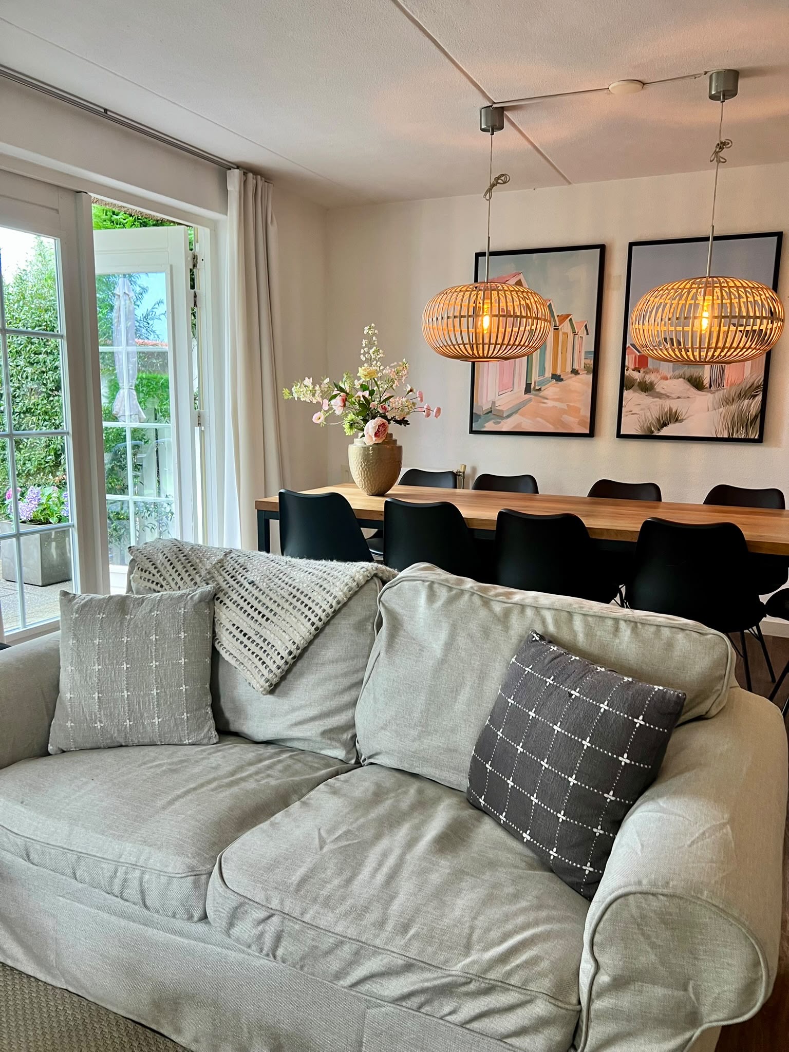 De gezellige zithoek, met de eettafel en de rieten hanglampen op de achtergrond