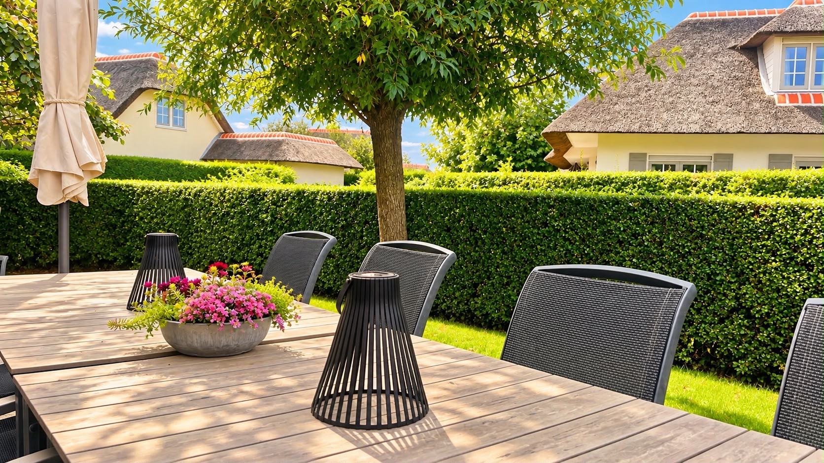 De tuintafel onder het bladerdak van de boom, met bloemen en lantaarns